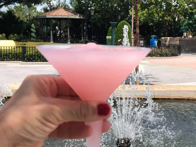 rose slushie in plastic glass in front of fountain 