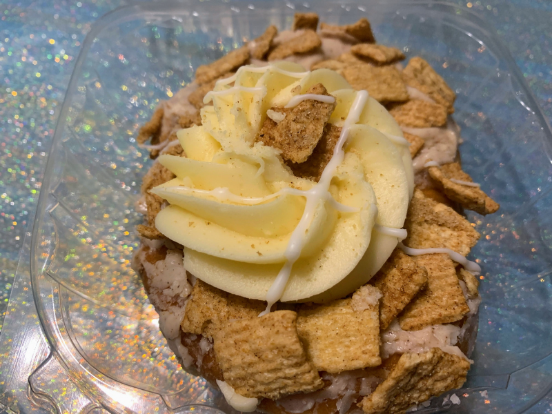 donut with cream cheese frosting and cinnamon toast crunch on top