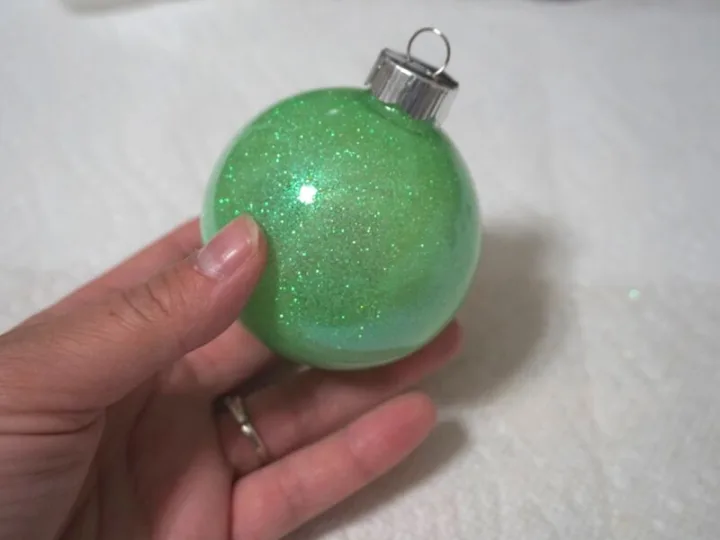 hand holding a green glitter decorated ornament 